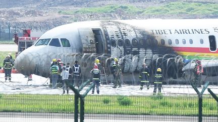 Des pompiers vérifient l'avion de la Tibet Airlines qui a pris feu après une sortie de piste, le 12 mai 2022 à&nbsp;Chongqing (Chine). (CNS / AFP)