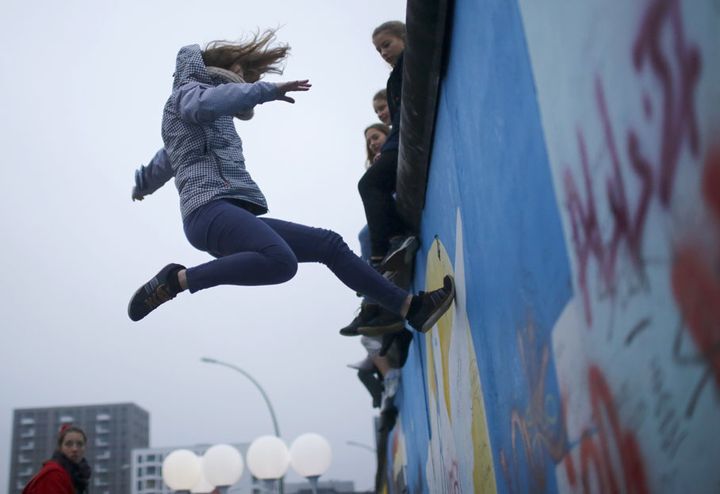 Un membre du Cirque sans frontières fait des accrobaties sur un trampoline devant l'East Side Gallery à Berlin (Allemagne) à l'occasion de la commémoration de la chute du Mur, le 9 novembre 2014. (HANNIBAL HANSCHKE / REUTERS)