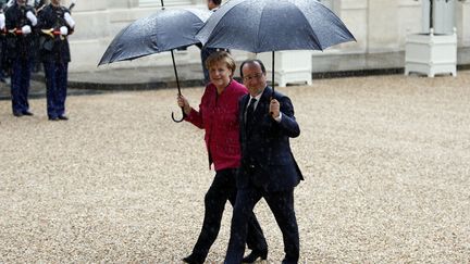 Le pr&eacute;sident fran&ccedil;ais, Fran&ccedil;ois Hollande (D) et la chanceli&egrave;re allemande, Angela Merkel arrivent sous la pluie au palais de l'Elys&eacute;e &agrave; Paris, le 30 mai 2013. (CHARLES PLATIAU / REUTERS)