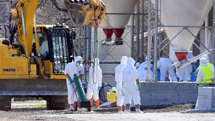 Des travailleurs portant une combinaison de protection désinfectent un élevage de volailles après la détection de la grippe aviaire, le 16 avril 2022,&nbsp;à Shiraoi (Chine). (NORIAKI SASAKI / YOMIURI / AFP)