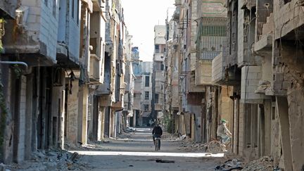 Un homme passe à vélo devant des bâtiments endommagés dans le camp de réfugiés de Yarmouk, dans la banlieue sud de la capitale syrienne, Damas, le 2 novembre 2022. (LOUAI BESHARA / AFP)