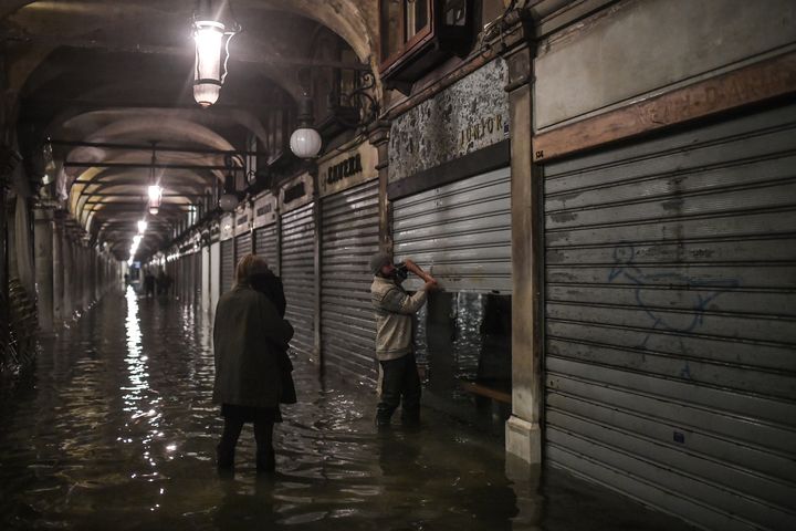 Un commerçant ferme son commerce, le 12 novembre 2019 à Venise (Italie). (MARCO BERTORELLO / AFP)