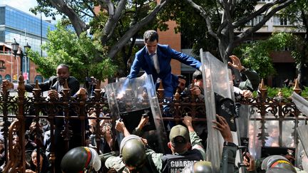 &nbsp;Juan Guaido tente d'escalader les grilles du Parlement vénézuélien le 5 janvier 2020 à Caracas (Venezuela). (FEDERICO PARRA / AFP)