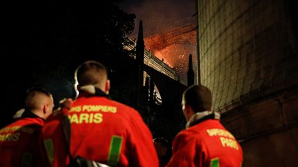 Des pompiers&nbsp;observent l'incendie qui ravage la toiture de la cathédrale Notre-Dame de Paris, le 15 avril 2019. (GEOFFROY VAN DER HASSELT / AFP)