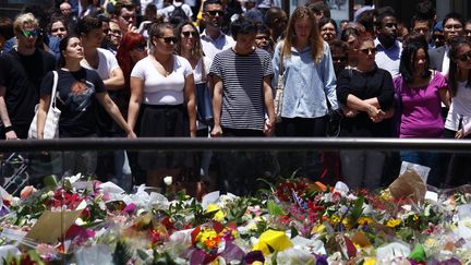 Des passants se recueillent, mardi 16 d&eacute;cembre 2014,&nbsp;devant le&nbsp;parterre de fleurs d&eacute;pos&eacute;es devant un caf&eacute; de Sydney (Australie), en hommage aux victimes de la prise d'otages qui s'y est d&eacute;roul&eacute;e la veille. (DAVID GRAY / REUTERS)