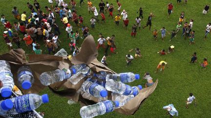 Un h&eacute;licopt&egrave;re militaire philippin lance des bouteilles d'eau &agrave; des survivants du typhon Haiyan &agrave; Tlosa (Philippines), le 21 novembre 2013. (ERIK DE CASTRO / REUTERS)