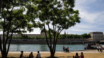 In Lyon, residents sit on the dry lawn of the city's quays, during a heat wave, on May 18, 2022. (OLIVIER CHASSIGNOLE / AFP)