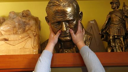 Un vendeur de souvenirs attrape un buste du pape Jean-Paul II dans son magasin &agrave; Kielce (Pologne), le 16 avril 2014. (KACPER PEMPEL / REUTERS)