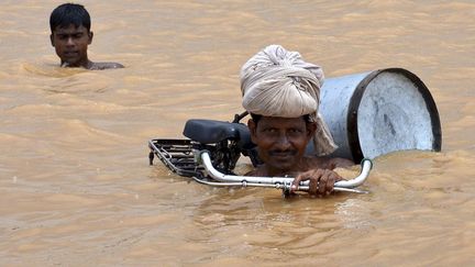 Un homme et son v&eacute;lo traversent une route inond&eacute;e par le Gange &agrave; Bihar (Inde), le 31 juillet 2013. (KRISHNENDU HALDER / REUTERS)