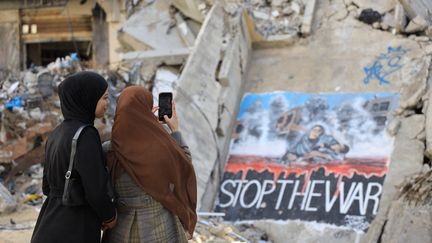 Des femmes devant les ruines d'un immeuble, dans la ville de Gaza, capitale de l'enclave palestienienne, le 21 décembre 2024. (MAHMOUD ISLEEM / ANADOLU / AFP)