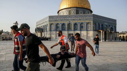 Des Palestiniens transportent une femme blessée sur l'esplanade des Mosquées à&nbsp;Jérusalem, le 27 juillet 2017. (AHMAD GHARABLI / AFP)