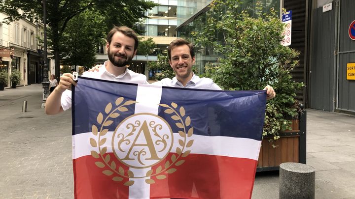 Antoine Paulet et Antoine Penhard, de la communauté Neurchi d'Antoine, avec le drapeau antoiniste. (THEO UHART / FRANCEINFO / RADIOFRANCE)