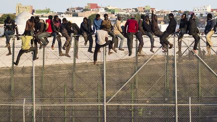 Des migrants africains perch&eacute;s sur une barri&egrave;re &agrave; la fronti&egrave;re entre le Maroc et l'Espagne attendent d'&ecirc;tre r&eacute;cup&eacute;r&eacute;s par des gardes civils espagnols qui les ont rep&eacute;r&eacute;s, Melilla (Espagne), le 22 octobre 2014. (REUTERS)