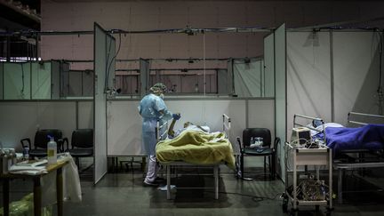 Un professionnel de santé auprès d'un patient au sein de l'hôpital de campagne installé dans&nbsp;une salle de sport de la ville de Portimao. (PATRICIA DE MELO MOREIRA / AFP)