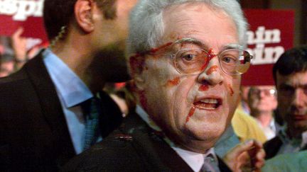 Le Premier ministre Lionel Jospin, candidat à l'élection présidentielle, aspergé&nbsp;de ketchup, le 17 avril 2002, lors de son arrivée au Parc des expositions de Rennes (Ille-et-Vilaine). (VALERY HACHE / AFP)