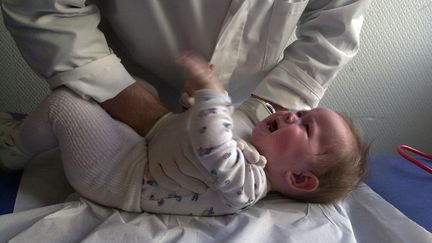 Un kinésithérapeute procure un massage respiratoire à un bébé de neuf mois atteint de bronchiolite (illustration). (MYCHELE DANIAU / AFP)