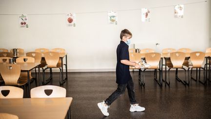 Un&nbsp;élève masqué portant son plateau repas dans&nbsp;la cantine d'un collège de Vincennes (Val-de-Marne), le 1er septembre 2020.&nbsp; (MARTIN BUREAU / AFP)