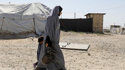 Une mère marche avec son enfant dans un camp du groupe Etat islamique dans le village&nbsp;Al-Malikiyah en Syrie, le 29 septembre 2018. (DELIL SOULEIMAN / AFP)