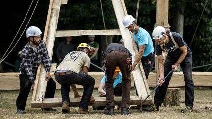 Des membres de Charpentiers sans frontières au travail sur la réplique d'une des structures de la nef de Notre-Dame, réalisée avec les techniques d'origine, à Ermenouville (Normandie, France), le 7 juillet 2020. (SAMEER AL-DOUMY / AFP)