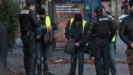 Des policiers procèdent à des fouilles de sacs de manifestants lors de la mobilisation des "gilets jaunes", à Paris, le 8&nbsp;décembre&nbsp;2018.&nbsp; (NURPHOTO / AFP)