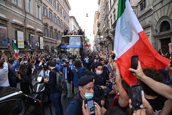 Les supporters italiens brandisent leur téléphone et des drapeaux au passage de leur équipe dans les rues de Rome, le 12 juillet 2021. (ANDREAS SOLARO / AFP)