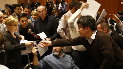 Une responsable de l'Agence mondiale antidopage distribue le rapport aux journalistes, le 9 novembre 2015 à Genève (Suisse). (DENIS BALIBOUSE / REUTERS)