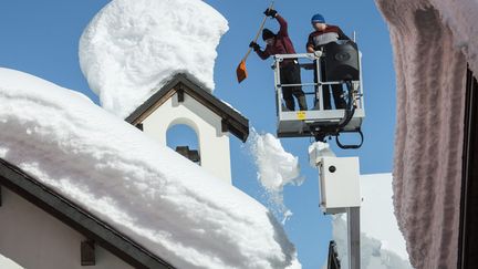 Des employ&eacute;s municipaux d&eacute;gagent la neige accumul&eacute;e sur les toits de Bedretto (Suisse), le 17 f&eacute;vrier 2014. (MAXPPP)