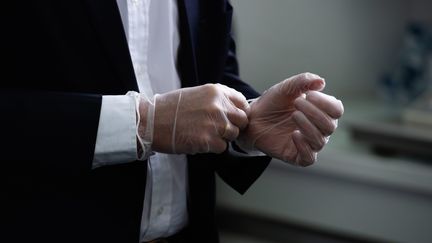 Un homme en costume porte des gants pour lutter contre la propagation du Covid-19 à Laval, le 6 mai 2020 (illustration).&nbsp; (DAVID ADEMAS / MAXPPP)