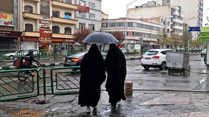 Deux femmes marchent dans une rue de Téhéran (Iran), le 5 décembre 2022. (ATTA KENARE / AFP)