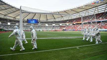 Des stadiers en combinaison enlèvent les cages du stade de Suzhou, le 13 avril 2021.&nbsp; (HECTOR RETAMAL / AFP)