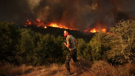 Un homme pendant une évacuation lors des incendies en Grèce, le 23 août 2023 à Maritsa. (AYHAN MEHMET / ANADOLU AGENCY / AFP)