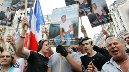 Des personnes brandissent des posters d'Ilan Halimi et le drapeau national lors d'un rassemblement, le 13 juillet 2009. (AFP)