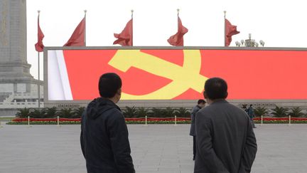 Deux Chinois devant le symbole du Parti communiste chinois, &agrave; P&eacute;kin (Chine), le 9 novembre 2012. (WANG ZHAO / AFP)