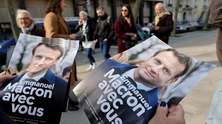 Des tracts pour la réélection d'Emmanuel Macron distribués dans une rue de Paris (France) le 5 mars 2022 (LUDOVIC MARIN / AFP)