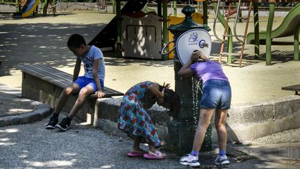 Des enfants boivent de l'eau en pleine canicule à Paris, le 21 août 2023. (MAGALI COHEN / HANS LUCAS / AFP)