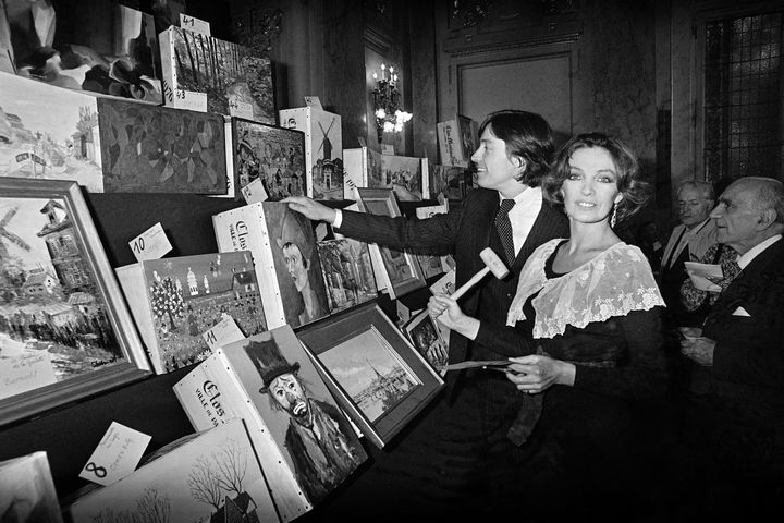 Le commissaire-priseur Pierre Cornette de St-Cyr assiste avec sa femme Marie Laforêt à la vente aux enchères du "Clos Montmartre 1976" le 6 octobre 1977 à Paris. De nombreux artistes ont personnalisé les caisses de six bouteilles dont cinquante ont été présentées aux enchères. (- / AFP)