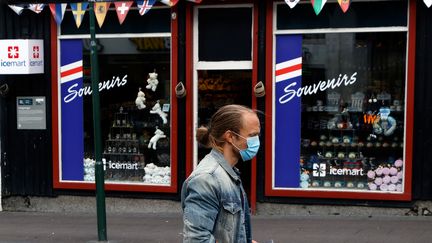 Un passant masqué devant un magasin de souvenirs aux couleurs du drapeau islandais à Reykjavik (Islande), le 3 septembre 2020. (JOHN SIBLEY / REUTERS)