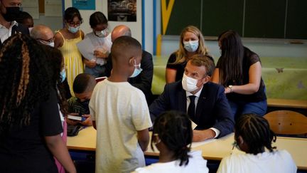 Emmanuel Macron échange avec un élève lors d'une visite dans une école à Marseille, le 2 septembre 2021. (DANIEL COLE / AFP)