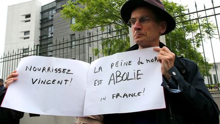 Un membre du comité de soutien du tétraplégique français Vincent Lambert, pancarte à la main, dimanche 19 mai lors d'une manifestation devant le CHU de Reims (FRANCOIS NASCIMBENI / AFP)