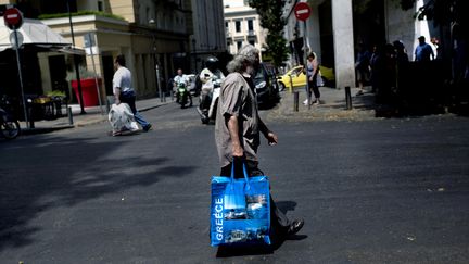 Un homme porte un sac dans une rue d'Ath&egrave;nes (Gr&egrave;ce) le 11 juillet 2015. (ANGELOS TZORTZINIS / AFP)