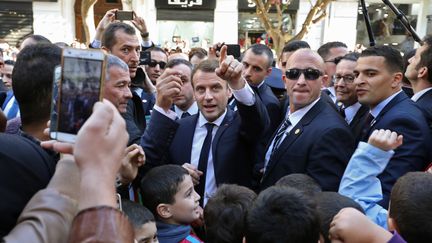 Le président français, Emmanuel Macron, entouré de gardes de sécurité, dans une rue d'Alger le 6 décembre 2017. (LUDOVIC MARIN / AFP)