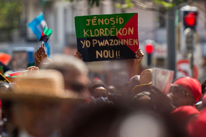 Un panneau dénonce : "génocide au chlordécone, ils nous ont empoisonnés", lors d'une manifestation à Fort-de-France (Martinique), le 27 février 2021. (LIONEL CHAMOISEAU / AFP)