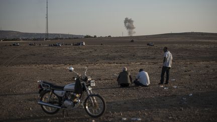 Trois hommes observent les combats entre l'Etat islamique et l'arm&eacute;e kurde &agrave; Koban&eacute; (Syrie), depuis les environs de la ville de Sanliurfa (Turquie), le 7 octobre 2014.&nbsp; (OZGE ELIF KIZIL / ANADOLU AGENCY / AFP)