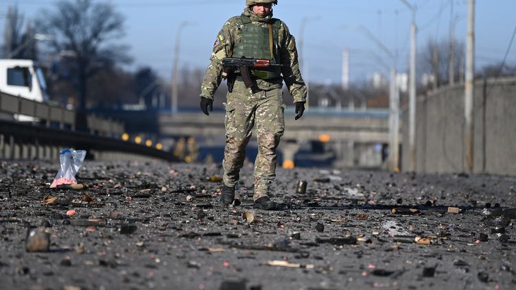 Un soldat ukrainien marche dans les débris qui couvrent le sol à l'ouest de Kiev le 26 février 2022. (DANIEL LEAL / AFP)