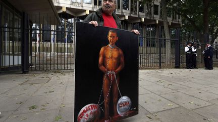 L'artiste engag&eacute; Kaya Mar pose devant l'ambassade am&eacute;ricaine &agrave; Londres (Royaume-Uni) avec un tableau repr&eacute;sentant en esclave&nbsp;le pr&eacute;sident am&eacute;ricain Barack Obama lors d'une manifestation de protestation contre une &eacute;ventuelle intervention militaire en Syrie, le 15 juin 2013. (LEFTERIS PITARAKIS / AP / SIPA)