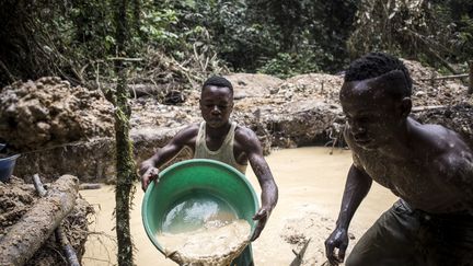 Des hommes recherchent des poussières d'or dans une mine artisanale en RDC, dans la province de l'Ituri. En une semaine de travail, ils vont récupérer au mieux six grammes d'or. (JOHN WESSELS / AFP)