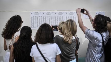 Des étudiants et parents consultent les résultats du baccalauréat, à Paris, le 5 juillet 2019. (STEPHANE DE SAKUTIN / AFP)