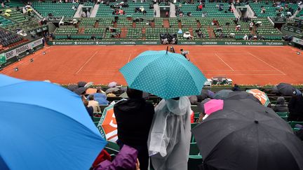 Des spectateurs du tournoi de Roland-Garros s'abritent sous un parapluie, à Paris. (ERIC FEFERBERG / AFP)