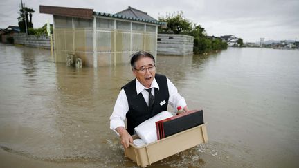 Un homme, de l'eau jusqu'&agrave; la taille, transporte des effets personnels dans une rue d'Oyama, dans la p&eacute;riph&eacute;rie nord de Tokyo (Japon), jeudi 10 septembre 2015. (KYODO NEWS / AP / SIPA)