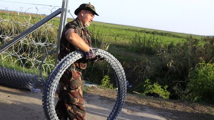 Un militaire hongrois apporte du c&acirc;ble barbel&eacute; pour monter une cl&ocirc;ture, &agrave; la fronti&egrave;re entre la Hongri et la Serbie, le 14 septembre 2015. (BERNADETT SZABO / REUTERS)